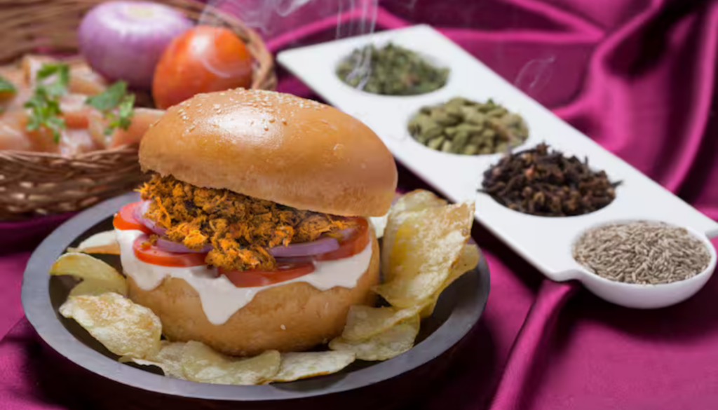 Juicy minced chicken infused with aromatic Indian spices, served on a soft bun with onions, tomato, and our signature sauce. Served with Chips and soda.